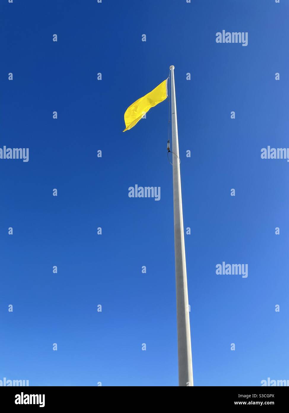 Yellow beach flag flying with deep blue sky background Stock Photo Alamy