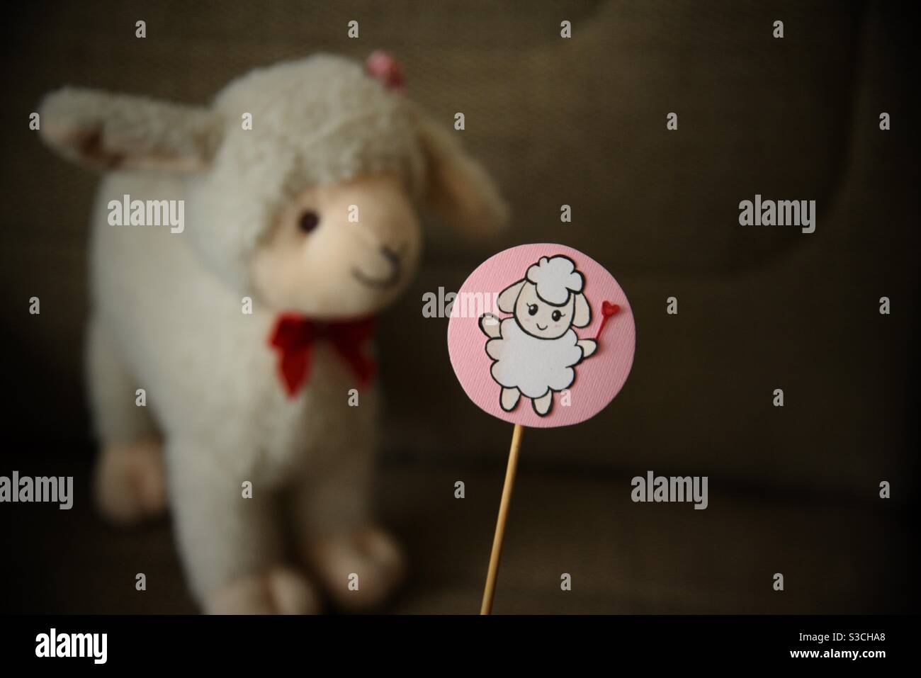 A handmade craft of a sheep and a sheep stuffed toy looking at it in the background - Smartphone Captured Stock Image