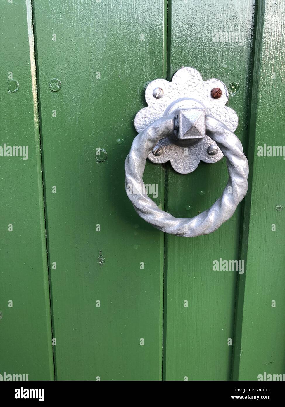 Silver ring door handle on a green, painted door - Smartphone Captured Stock Image