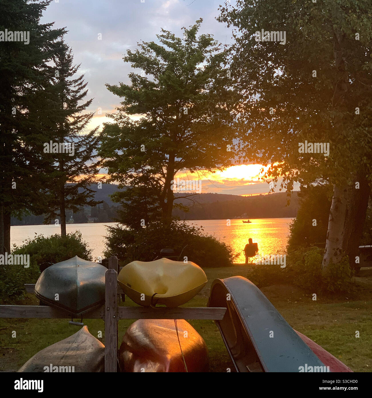 Canoes overlooking Back Lake and a man watching the sunset at the Tall