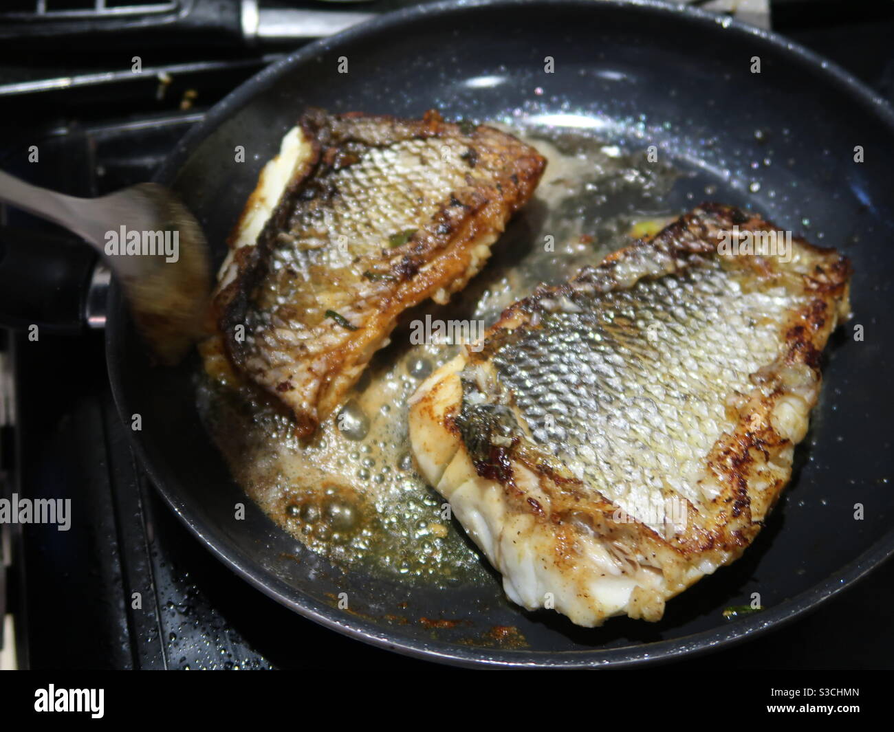 Sea bass fillets being pan fried Stock Photo Alamy