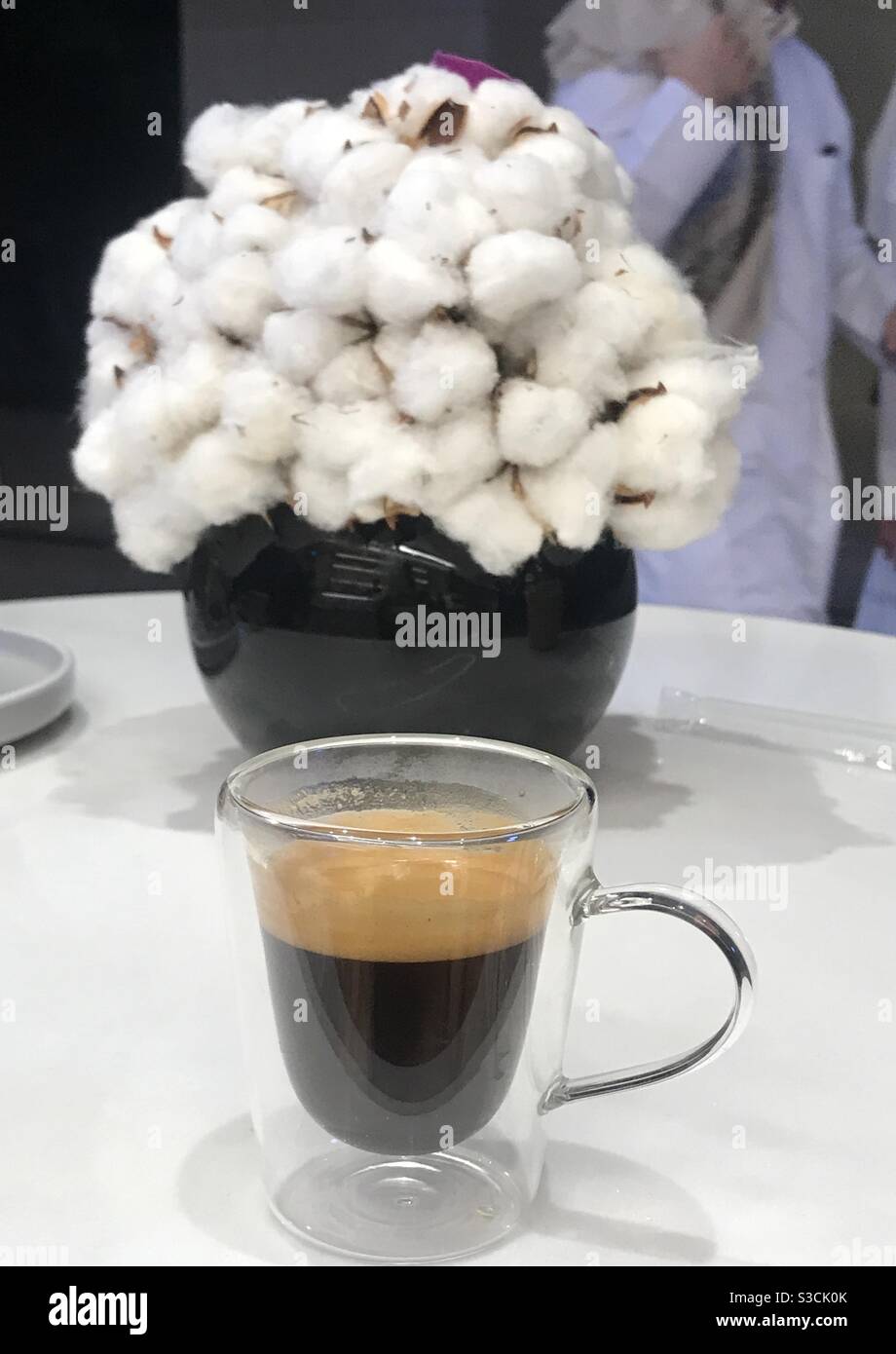 Cup of espresso coffee with a cotton plant in the background of a cafe in downtown Doha, Qatar - Smartphone Captured Stock Image