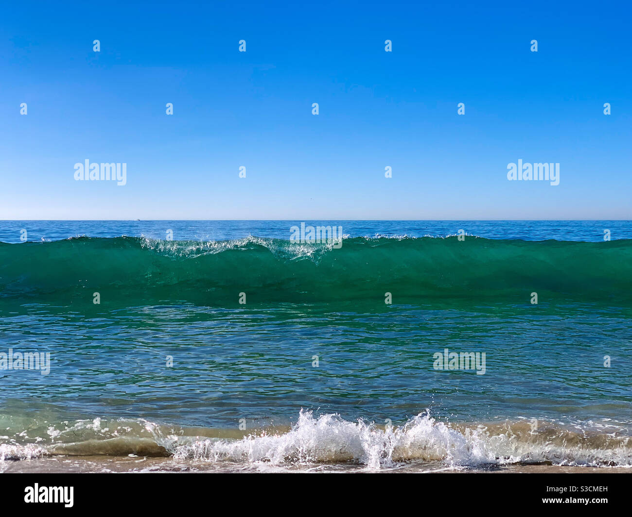 Ocean waves breaking onto sandy beach on a sunny day. - Smartphone Captured Stock Image