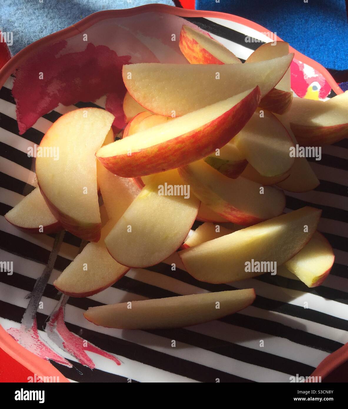 Close up of a sliced apple on a decorative striped plate - Smartphone Captured Stock Image