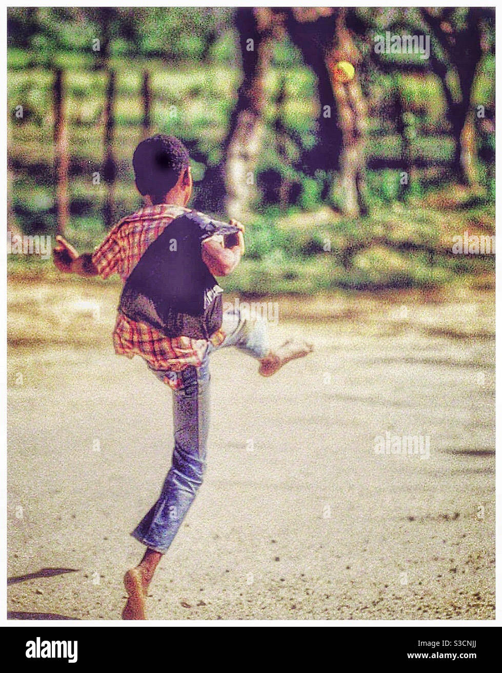A Jamaican boy plays with a tennis ball. - Smartphone Captured Stock Image