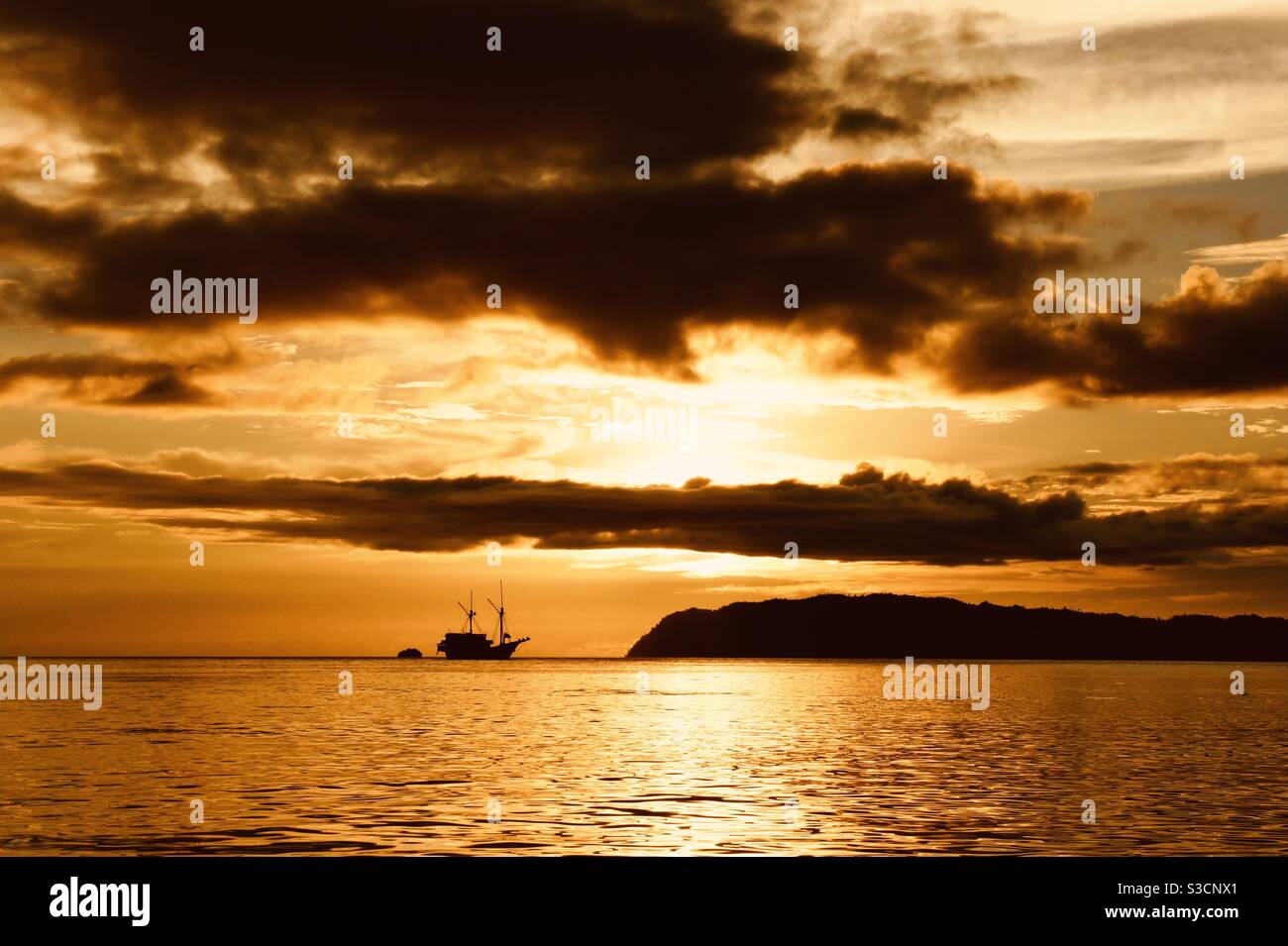 Orange sunset with boat on the horizon Raja Ampat Indonesia Stock Photo