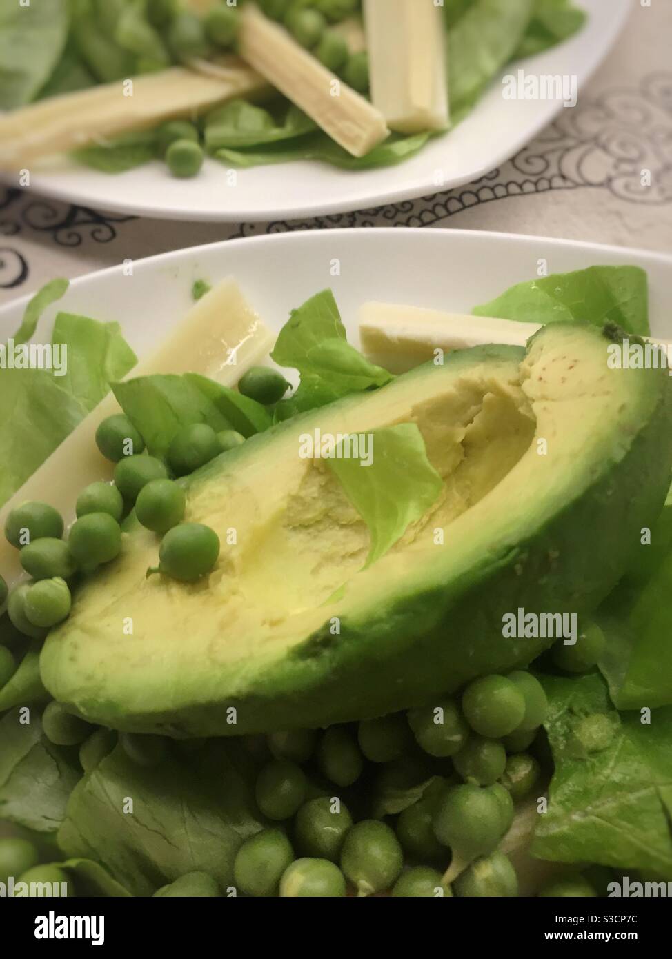 Close up of a healthy salad of avocado, hearts of palm, fresh peas on a bed of lettuce - Smartphone Captured Stock Image