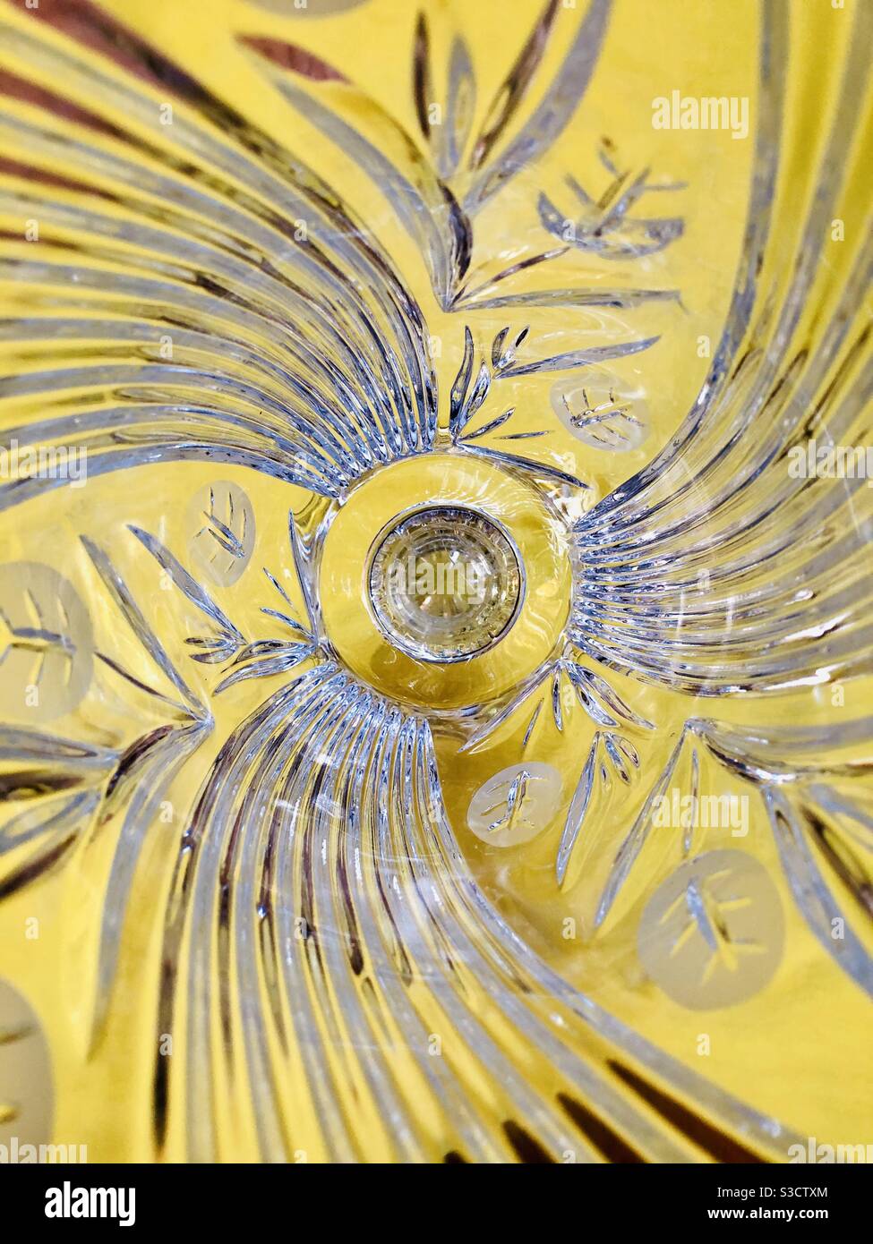 Looking inside an intricately patterned glass flower vase on yellow background - Smartphone Captured Stock Image