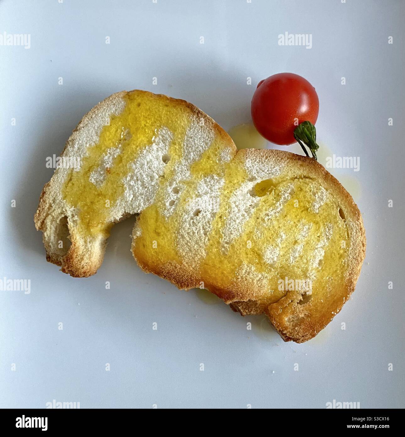 Toast of bread with olive oil and a cherry tomato Stock Photo
