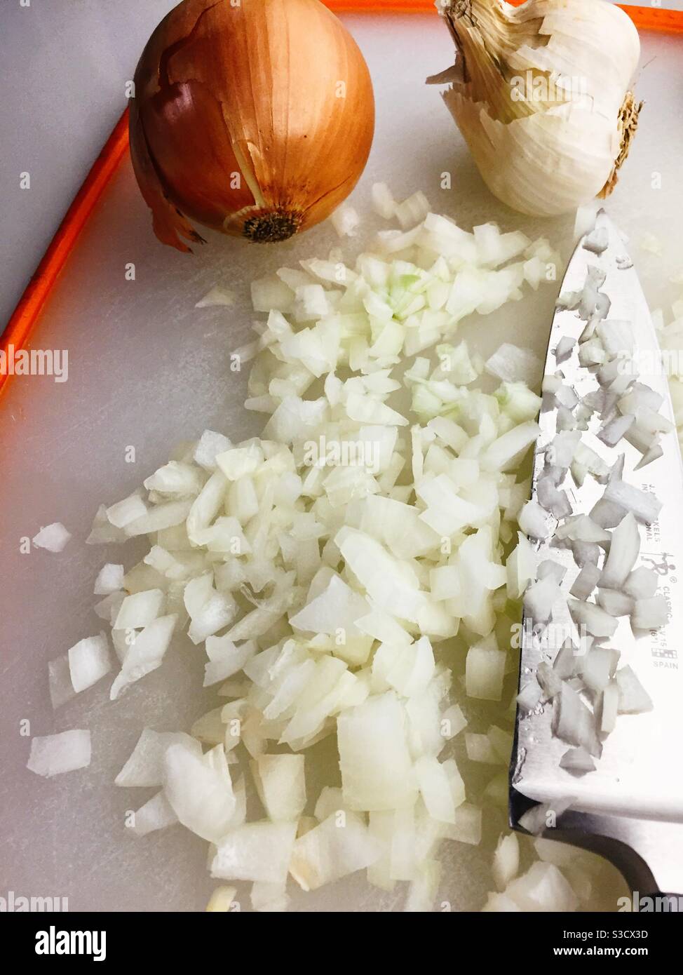 Freshly chopped raw onion and French chef knife on a residential kitchen cutting board, USA - Smartphone Captured Stock Image