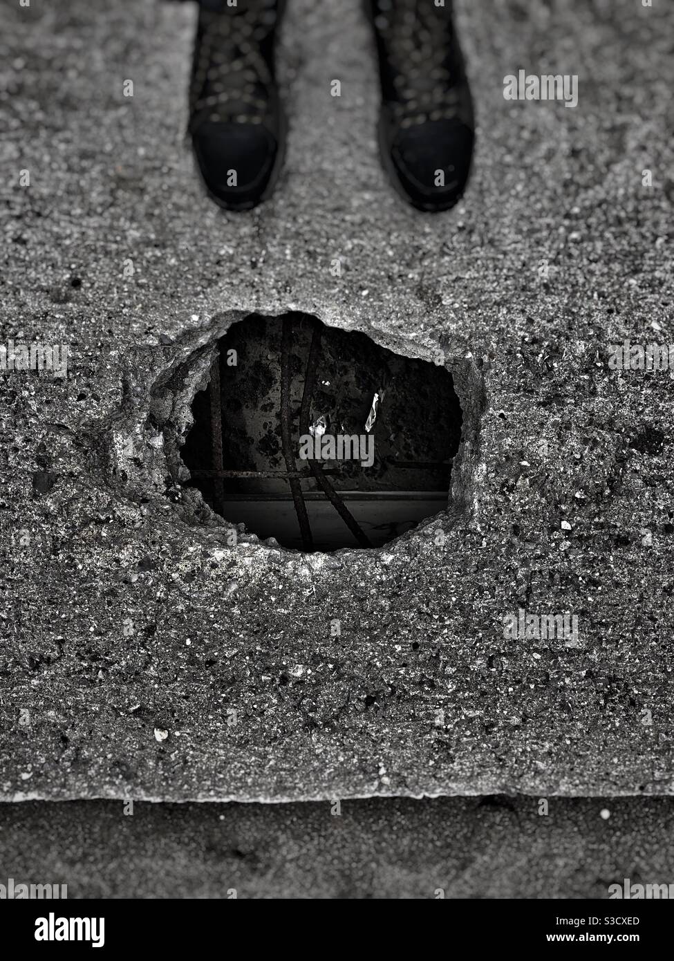 Man standing in front of a hole on a cracked concrete floor - Smartphone Captured Stock Image