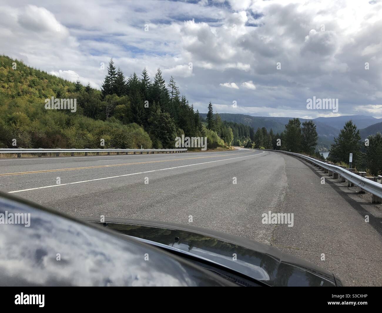 I can’t wait to be on the road again! Here’s the view driving into the Cascades forest mountains outside of Portland Oregon USA on a cloudy afternoon. - Smartphone Captured Stock Image