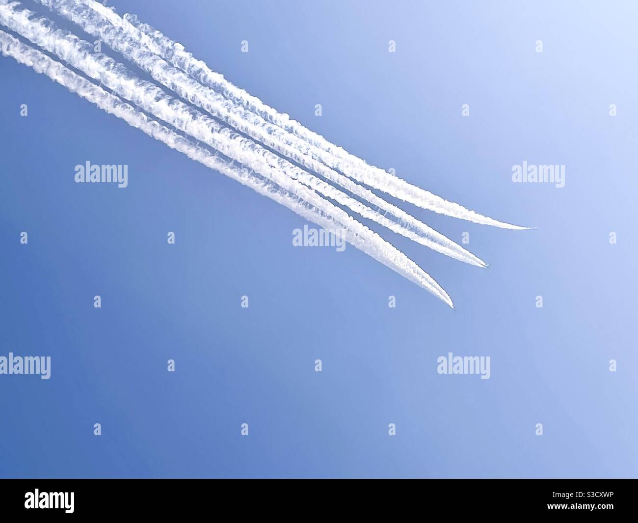 Three smoke trails created by fighter jets in blue sky Stock Photo