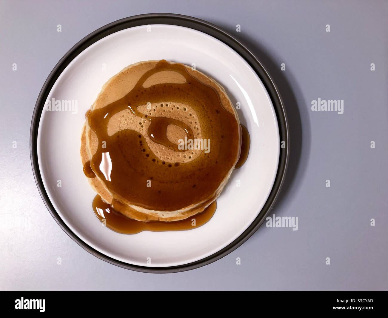 Two pancakes with maple syrup on a plate. - Smartphone Captured Stock Image