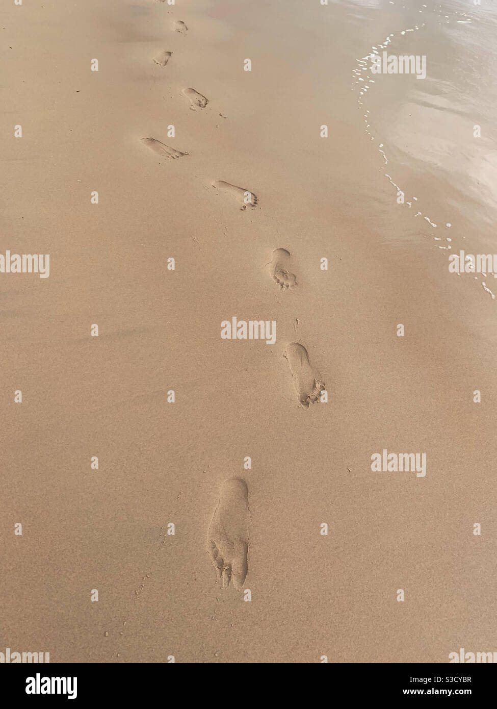 A curving line of footprints in the sand on the beach. Not walking in a straight line - Smartphone Captured Stock Image