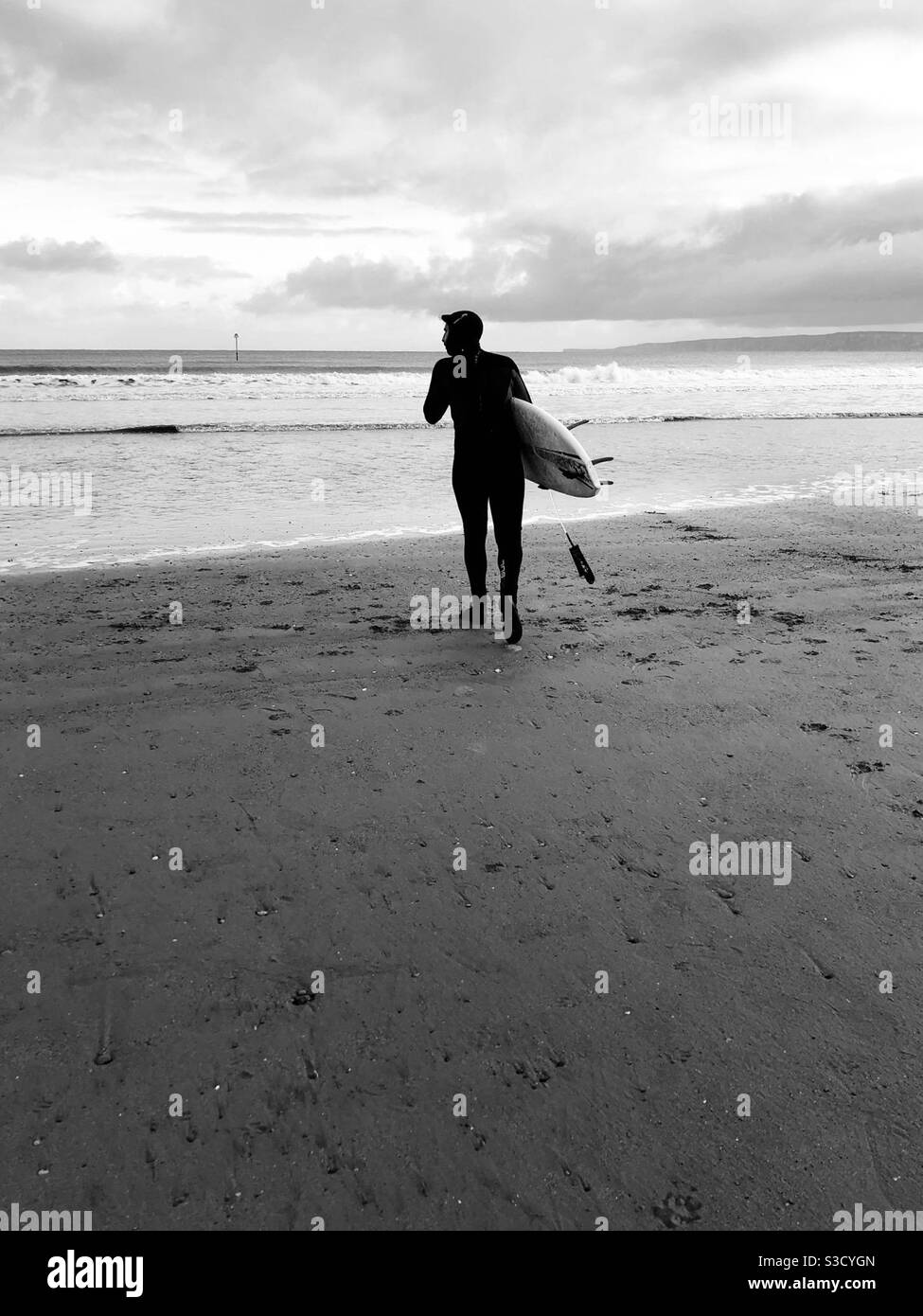 Black and white image of a surfer setting out on a cold, winter’s day - Smartphone Captured Stock Image