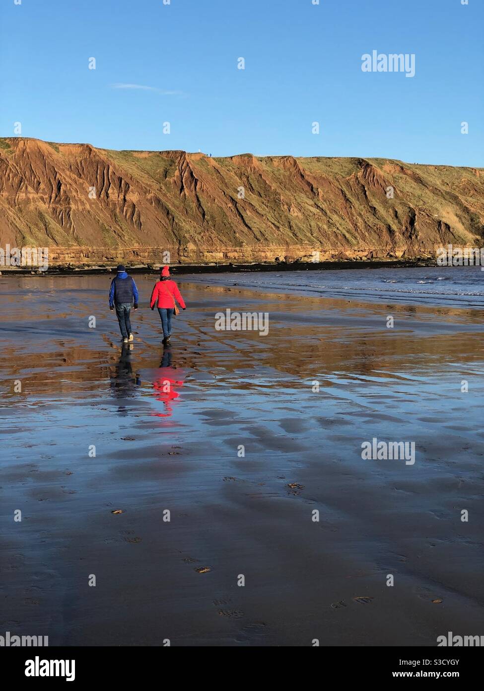 Couple walking along a beach during winter lockdown - Smartphone Captured Stock Image