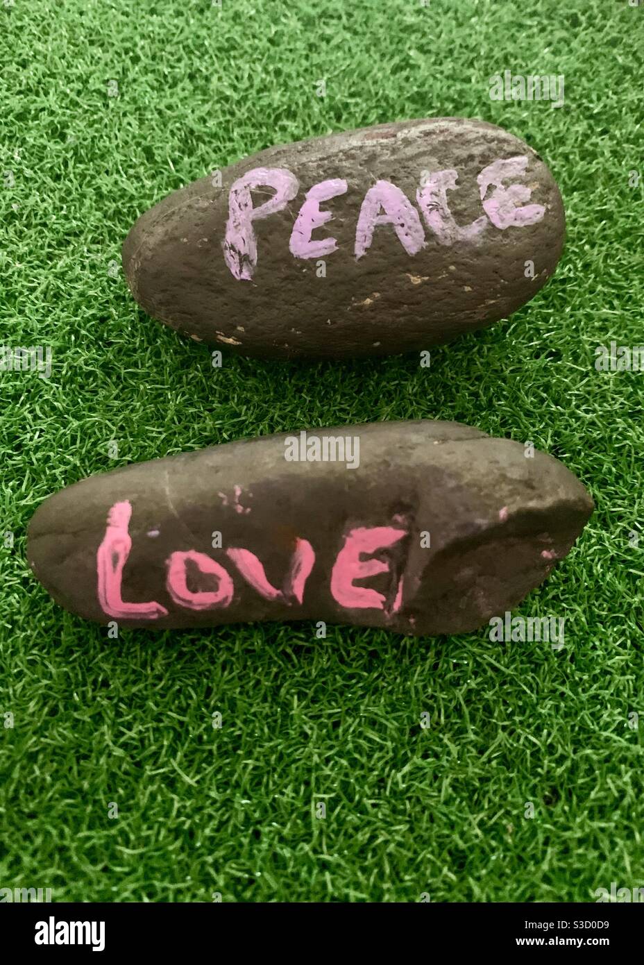 Painted Peace rocks - rocks with the words peace and love painted on them displayed on green grass. World peace and equal rights - love one another Stock Photo