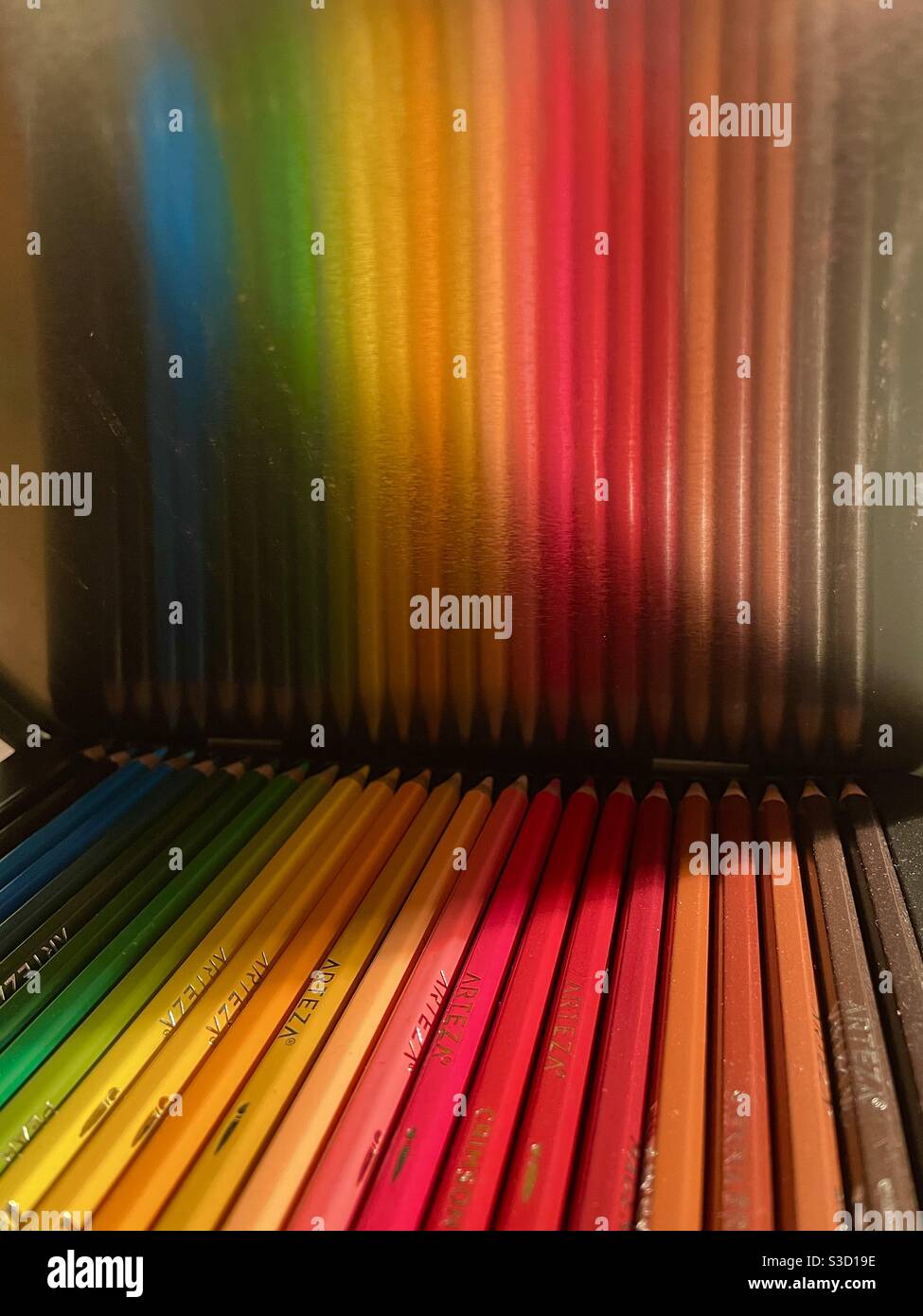 A rainbow of colored pencils reflected in the metal case. - Smartphone Captured Stock Image