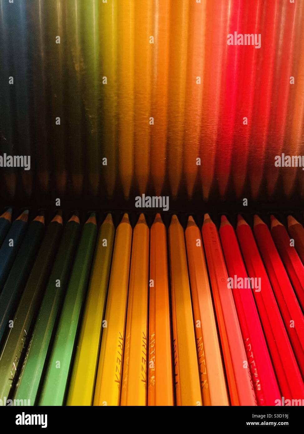 Colored pencils are reflected in the metal lid holding them, a rainbow of colors! - Smartphone Captured Stock Image