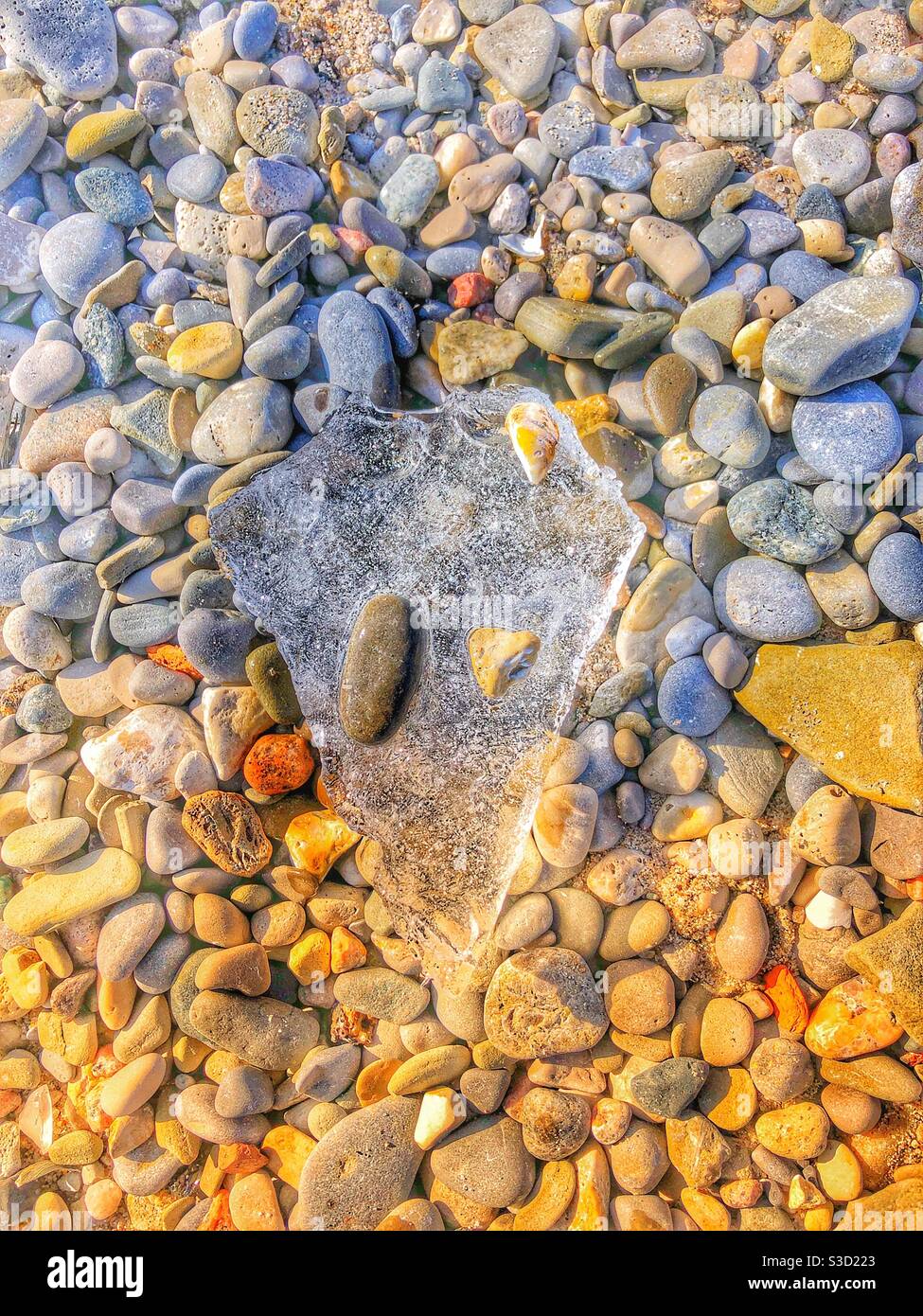 A high angle view of floating ice floating over rocks. - Smartphone Captured Stock Image