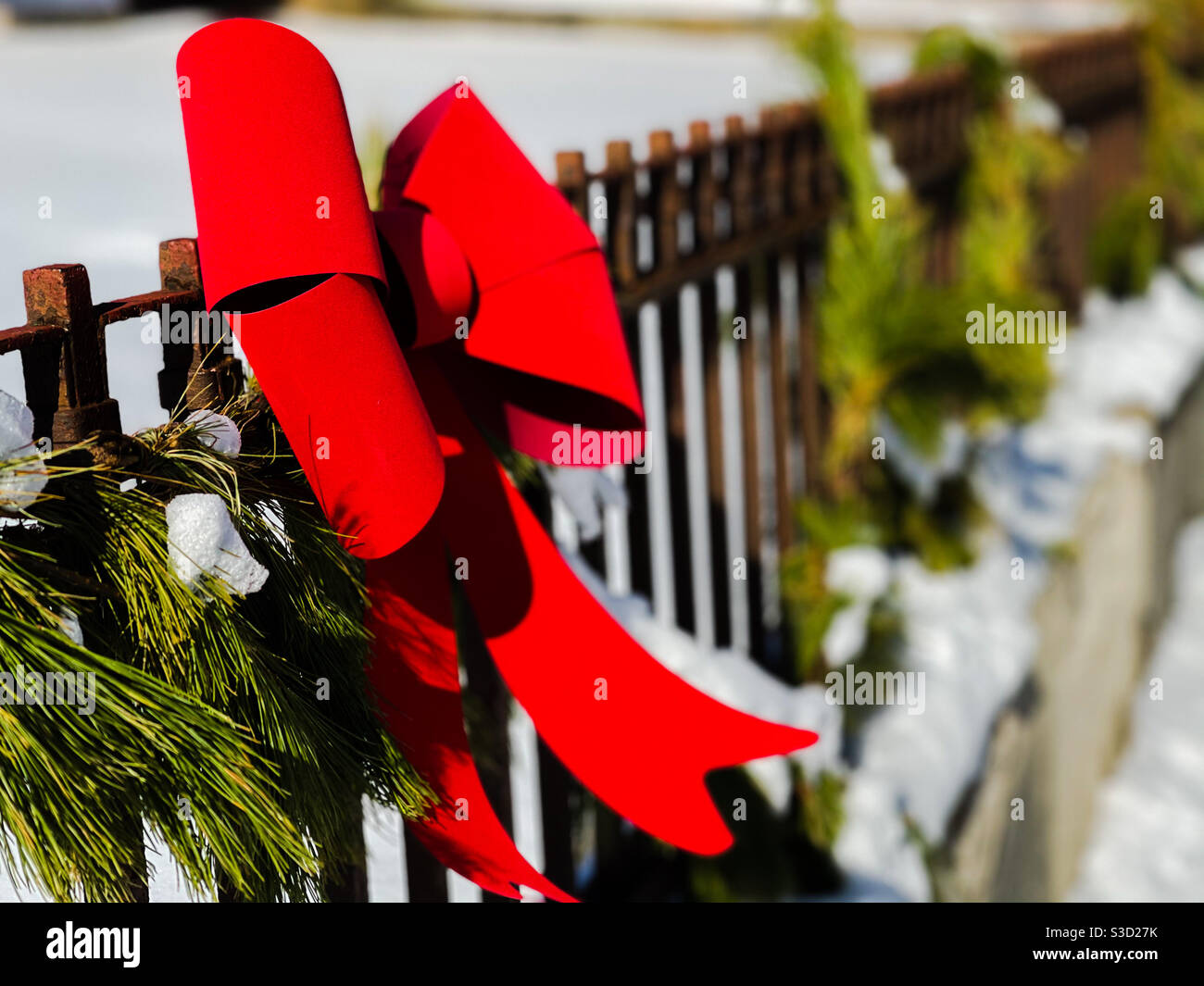 Red Christmas bow on fence. Stock Photo