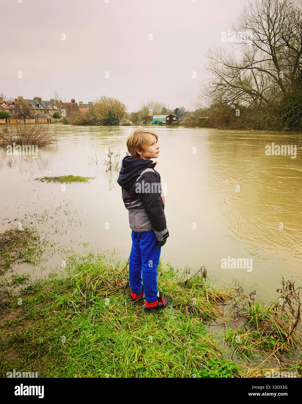 Boy standing by a flooded river - Smartphone Captured Stock Image