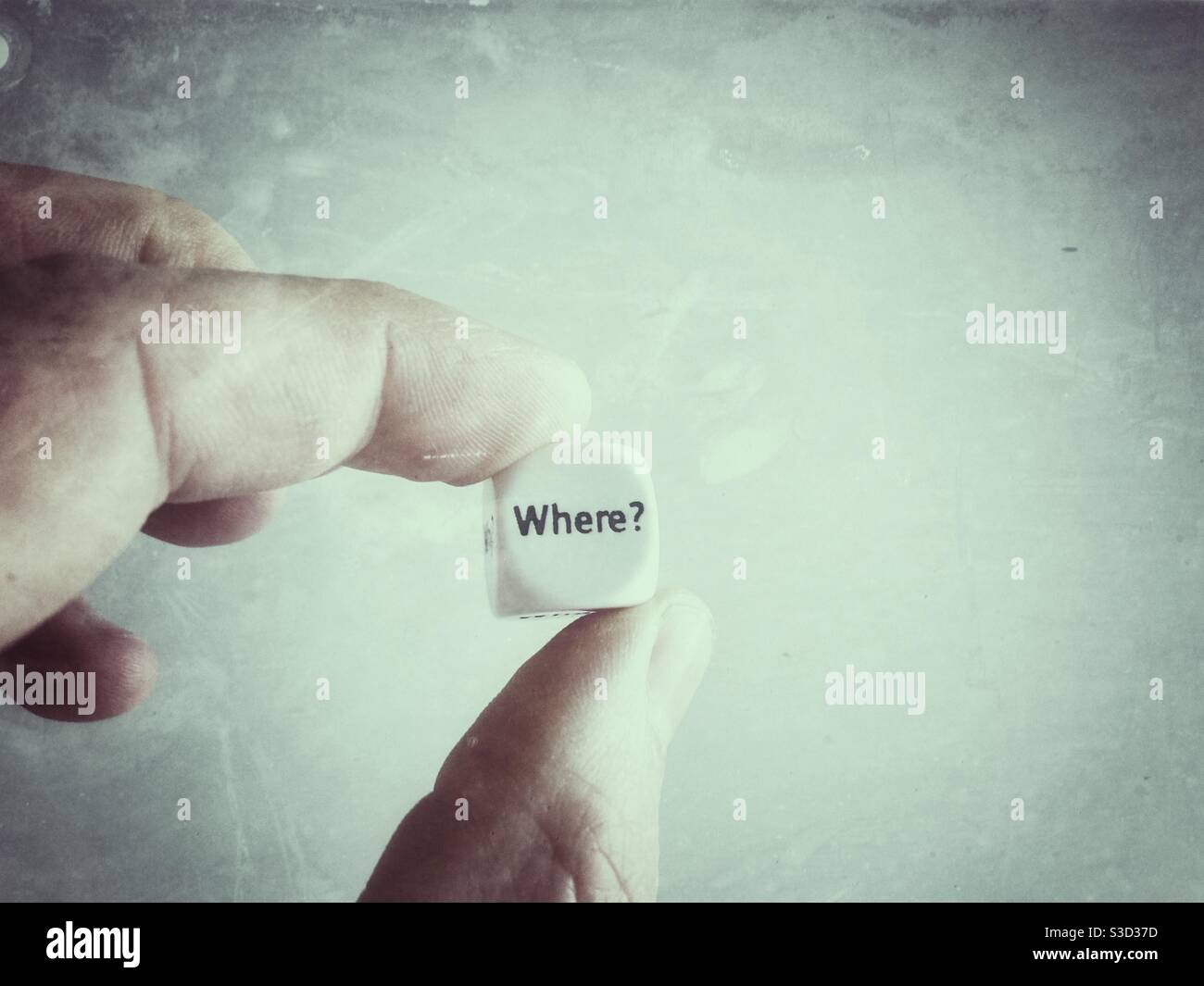 A Male Hand holding a die with the question Where? - Smartphone Captured Stock Image