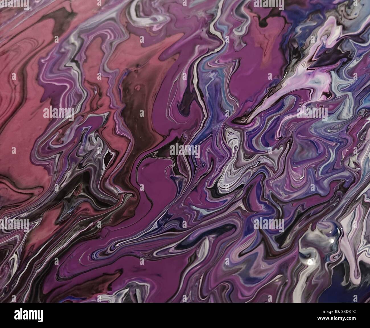 A photograph of paint texture in swirls in an abstract pattern on a canvas. Fluid art, in muted purple and pink tones - Smartphone Captured Stock Image