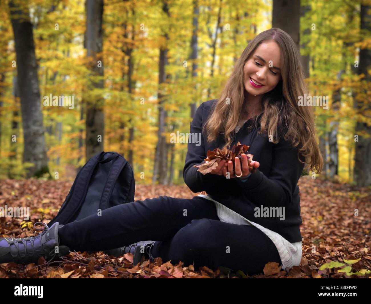 Young woman in the forest holding autumn leaves in her hands - Smartphone Captured Stock Image