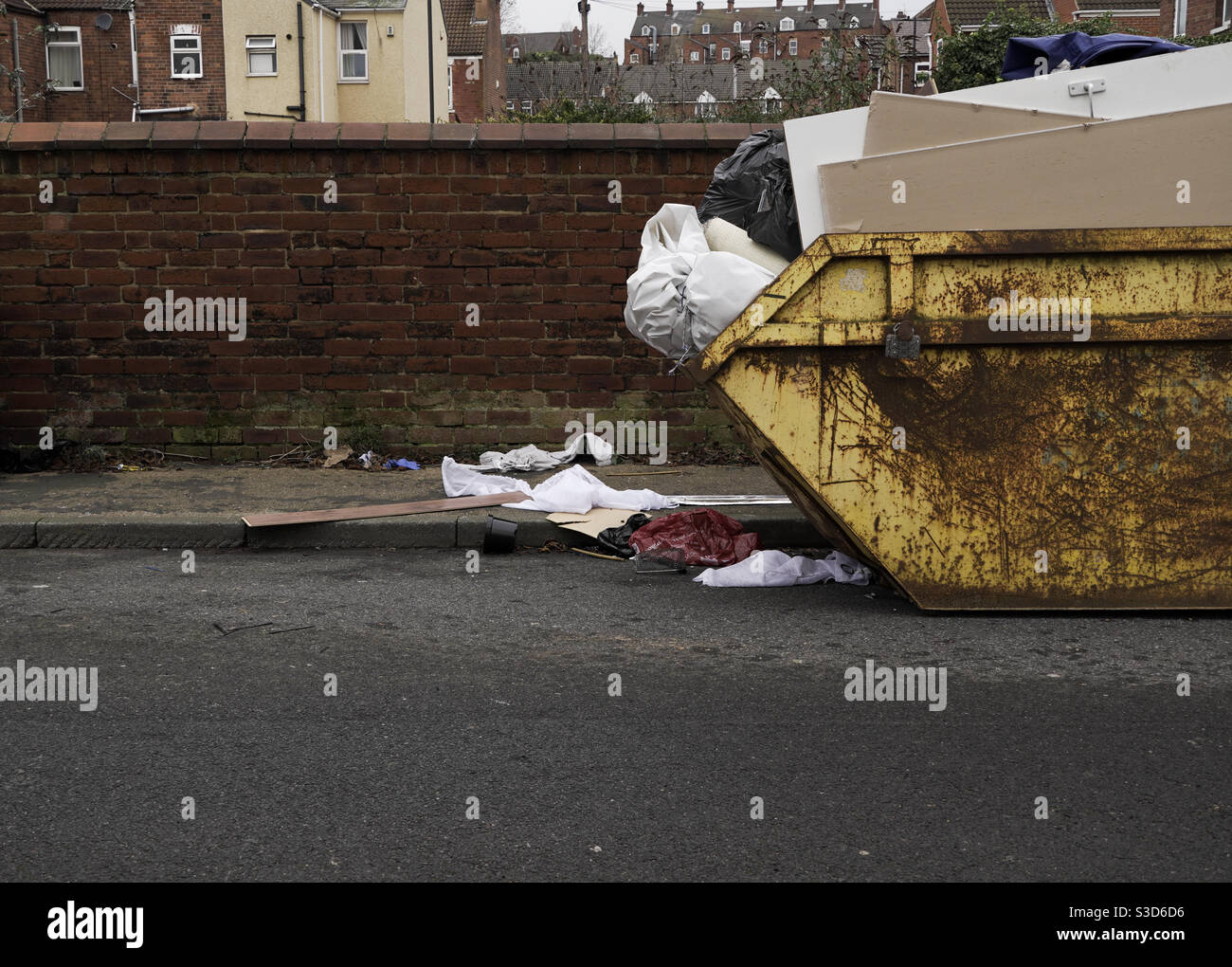 An overflowing full skip on the side of the road with copy space Stock Photo