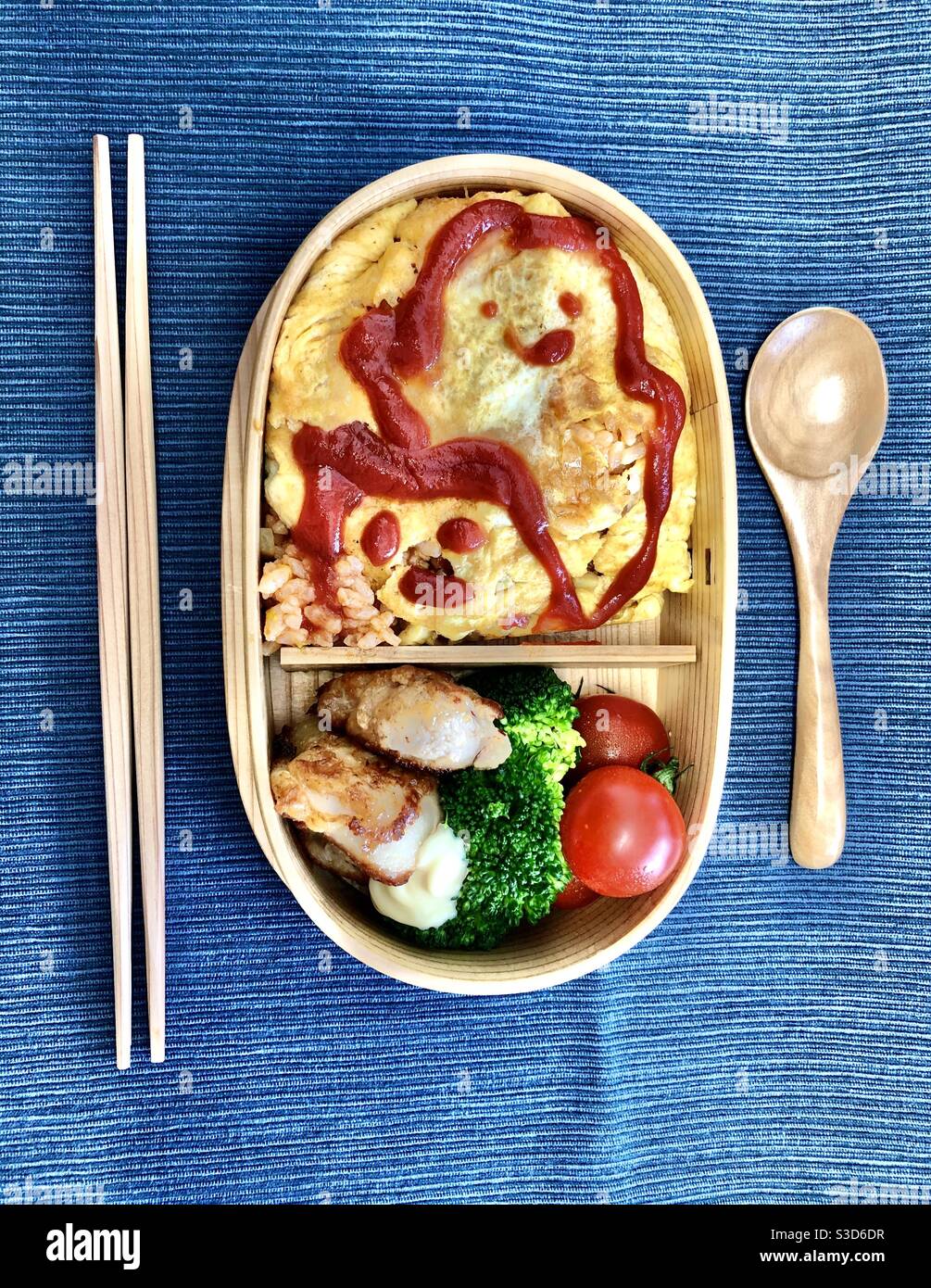 Homemade bento box lunch in a magewappa cedar box on a blue tablecloth - Smartphone Captured Stock Image