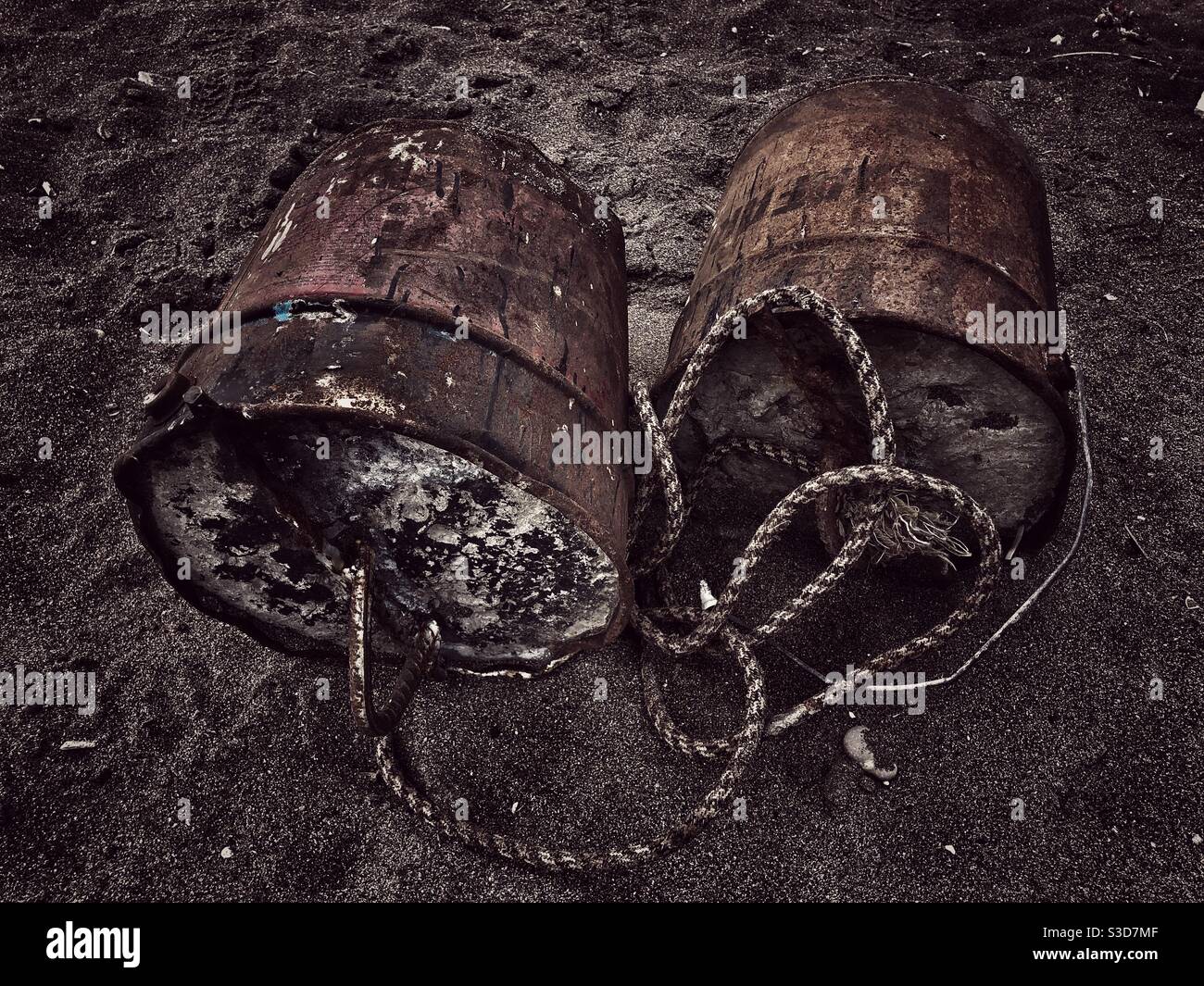 Two rust my buckets that are filled with concrete tied to each other - Smartphone Captured Stock Image