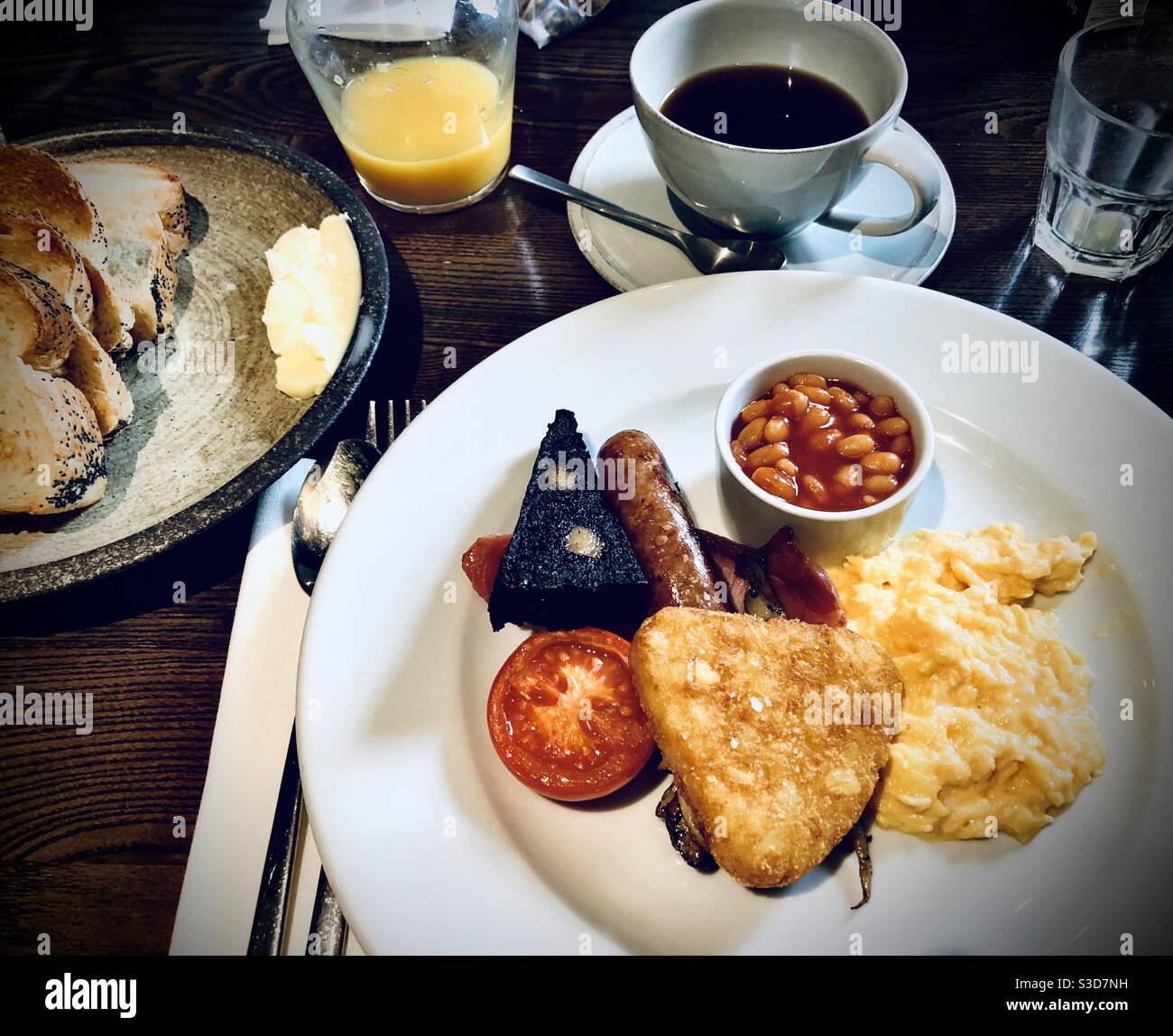 Full English breakfast served on a large white plate on a wooden table - Smartphone Captured Stock Image
