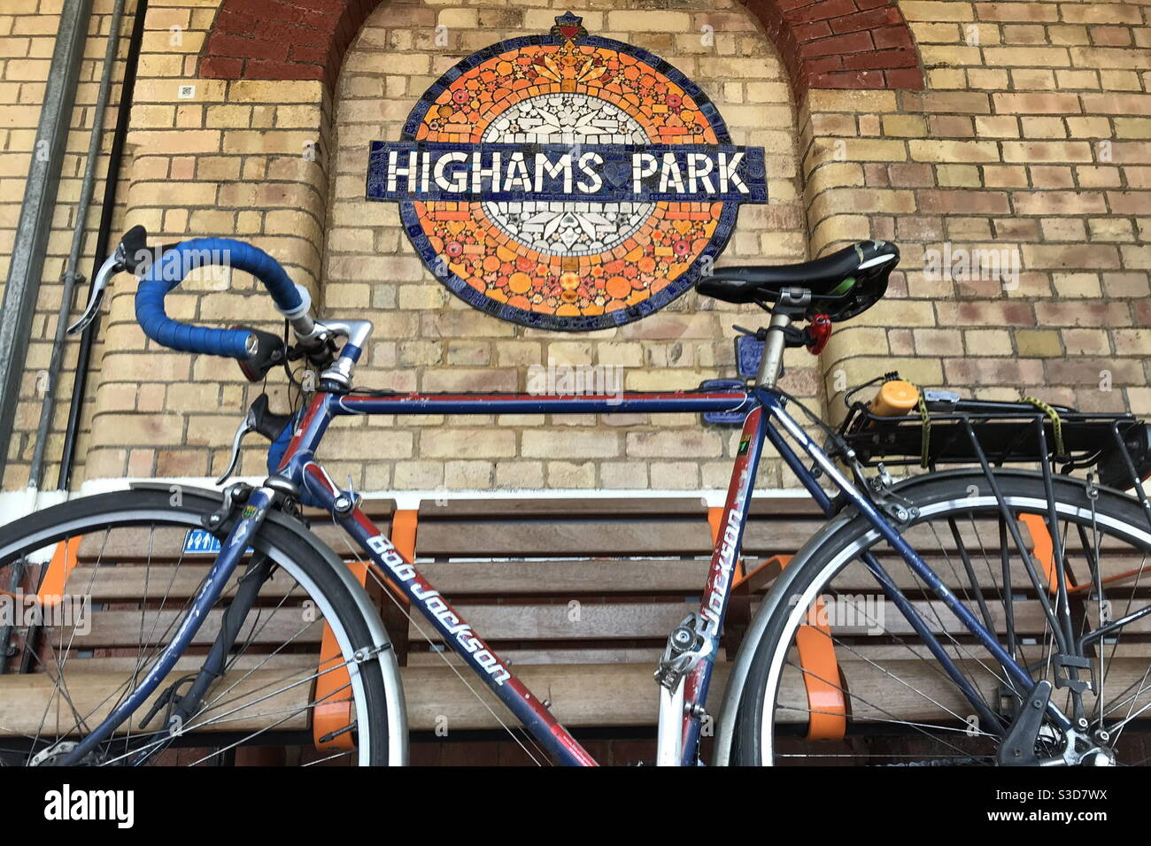 A Bob Jackson road bicycle is seen in front of a mosaic roundel at Highams Park Weaver Line station in northeast London - Smartphone Captured Stock Image