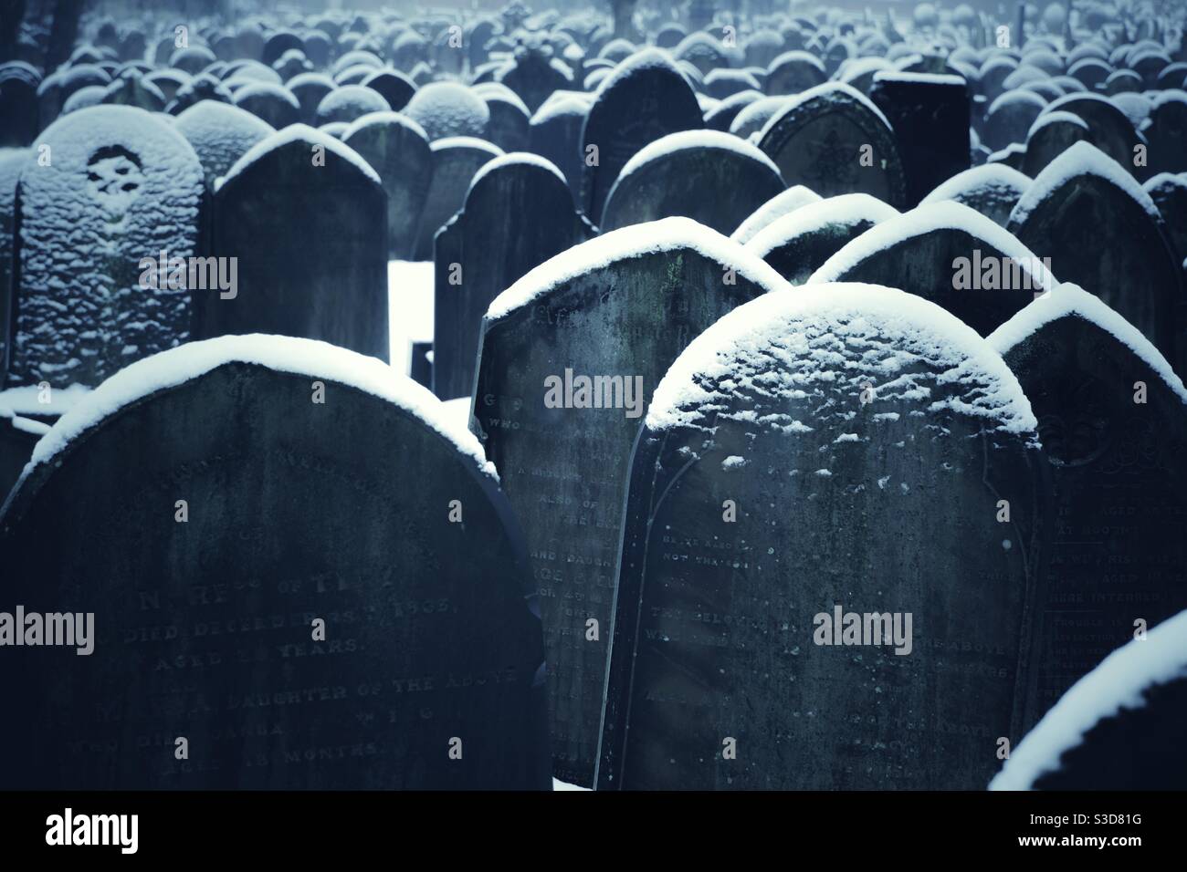 Full frame religious background of gravestones in a cemetery covered in cold snow in a Winter scene Stock Photo