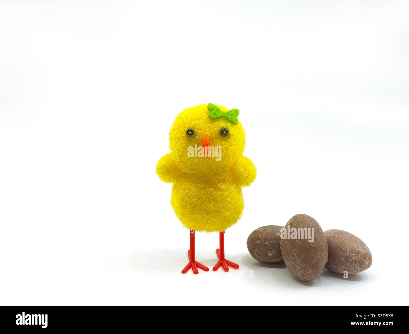 Cute model chick with small chocolate Easter eggs isolated on a plain white background - Smartphone Captured Stock Image