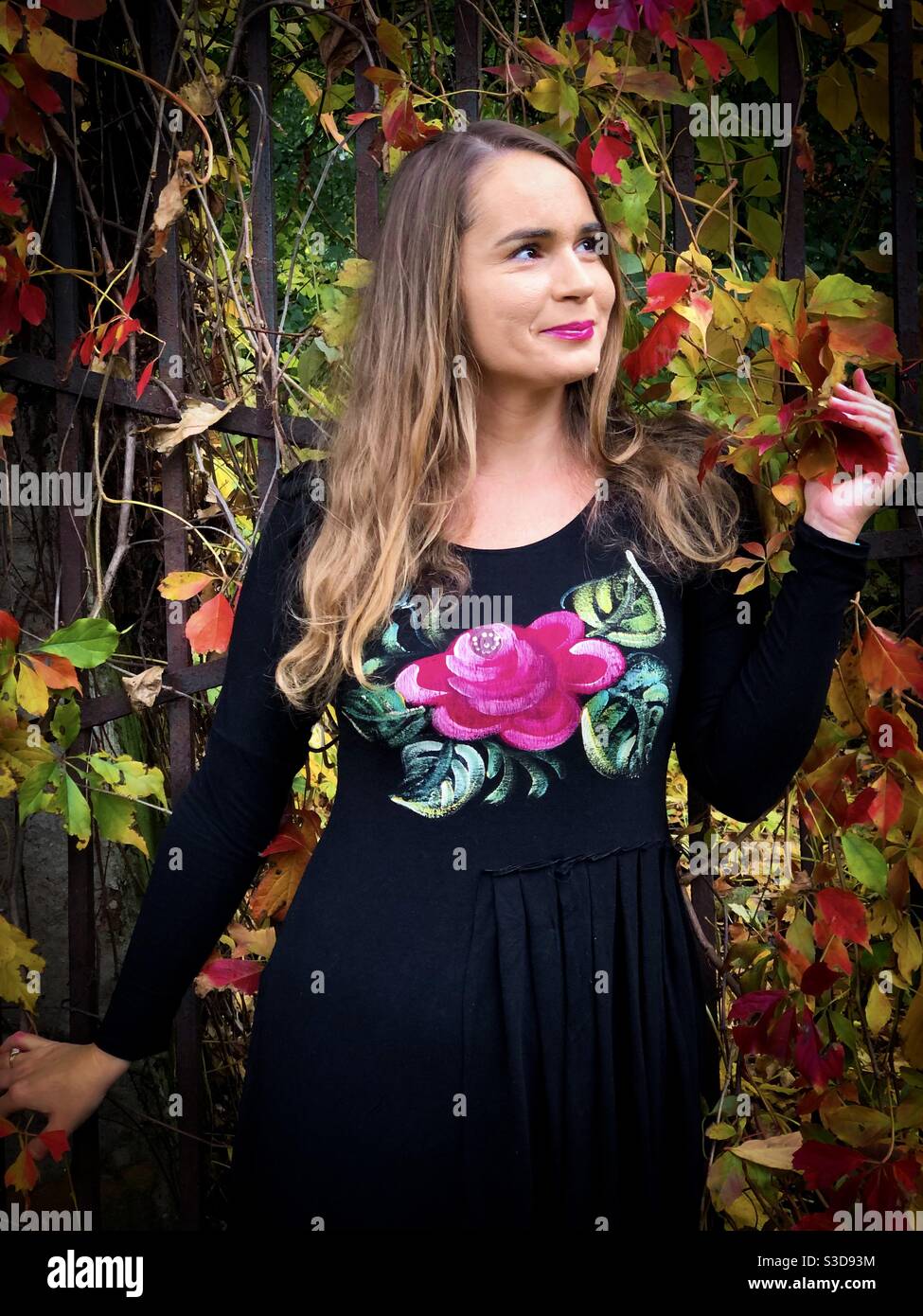 Young woman surrounded by colorful ivy leaves in autumn - Smartphone Captured Stock Image