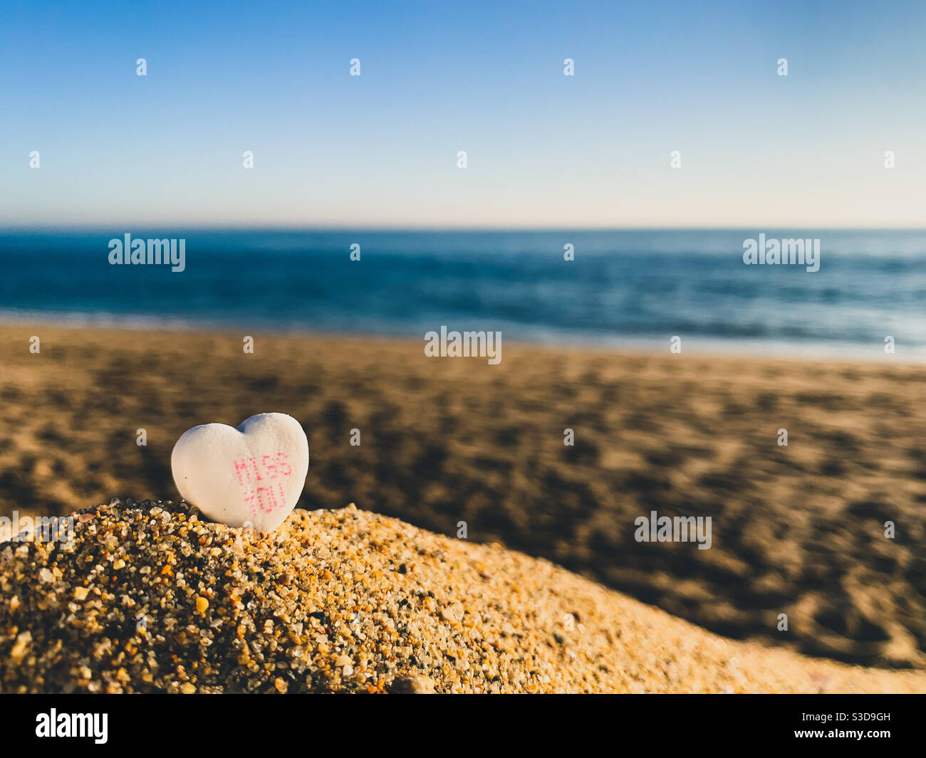Valentine candy heart on a beach during golden hour of a beautiful sunny evening. - Smartphone Captured Stock Image