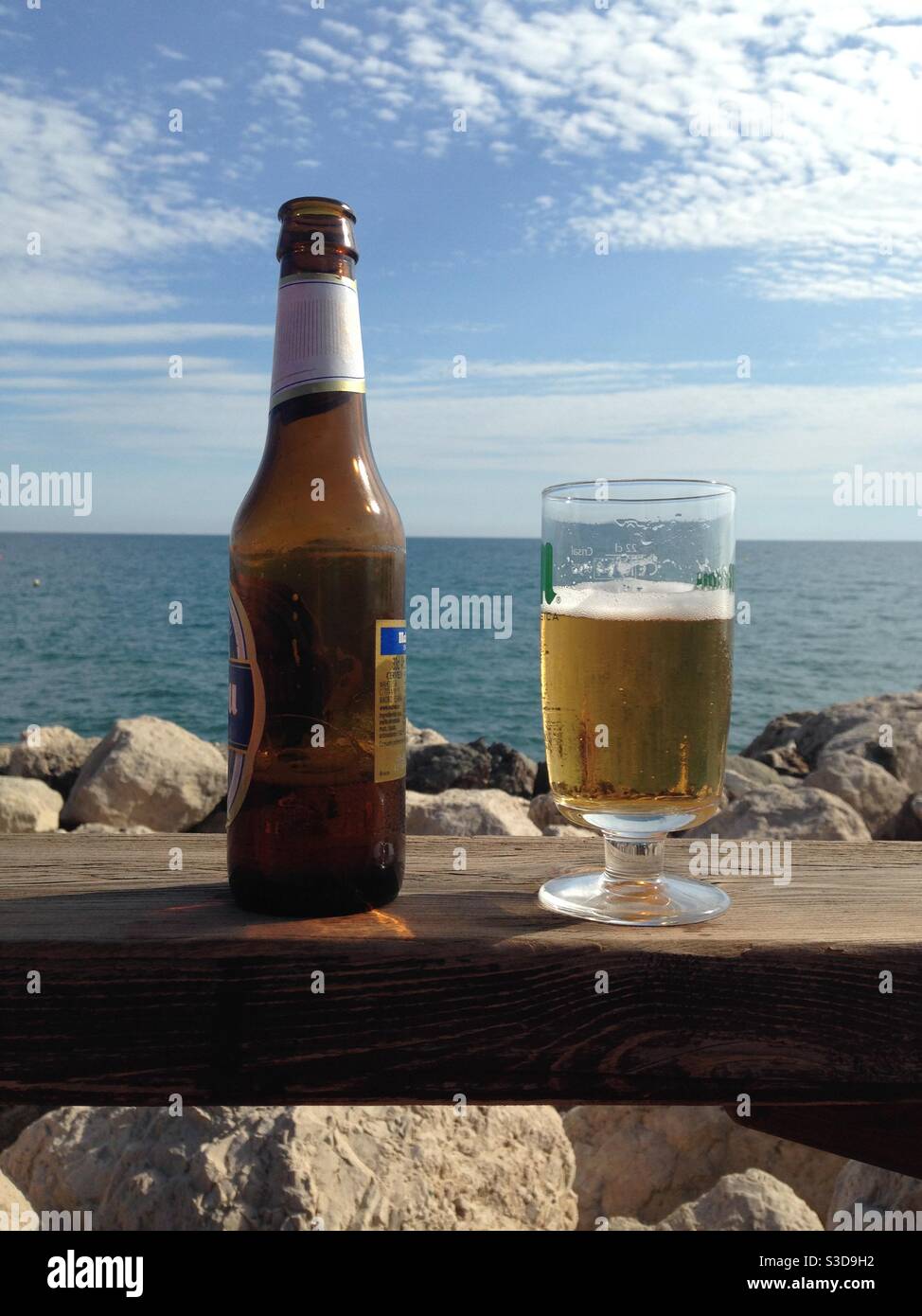 Bottle and glass of beer in front of blue sea and sky - Smartphone Captured Stock Image