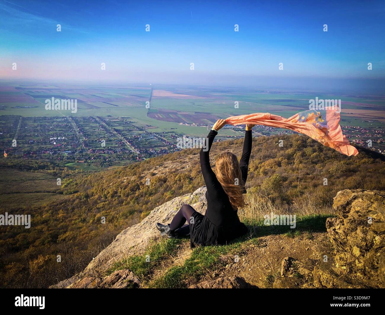 Woman standing on the edge of a cliff holding a scarf blowing in the wind - Smartphone Captured Stock Image