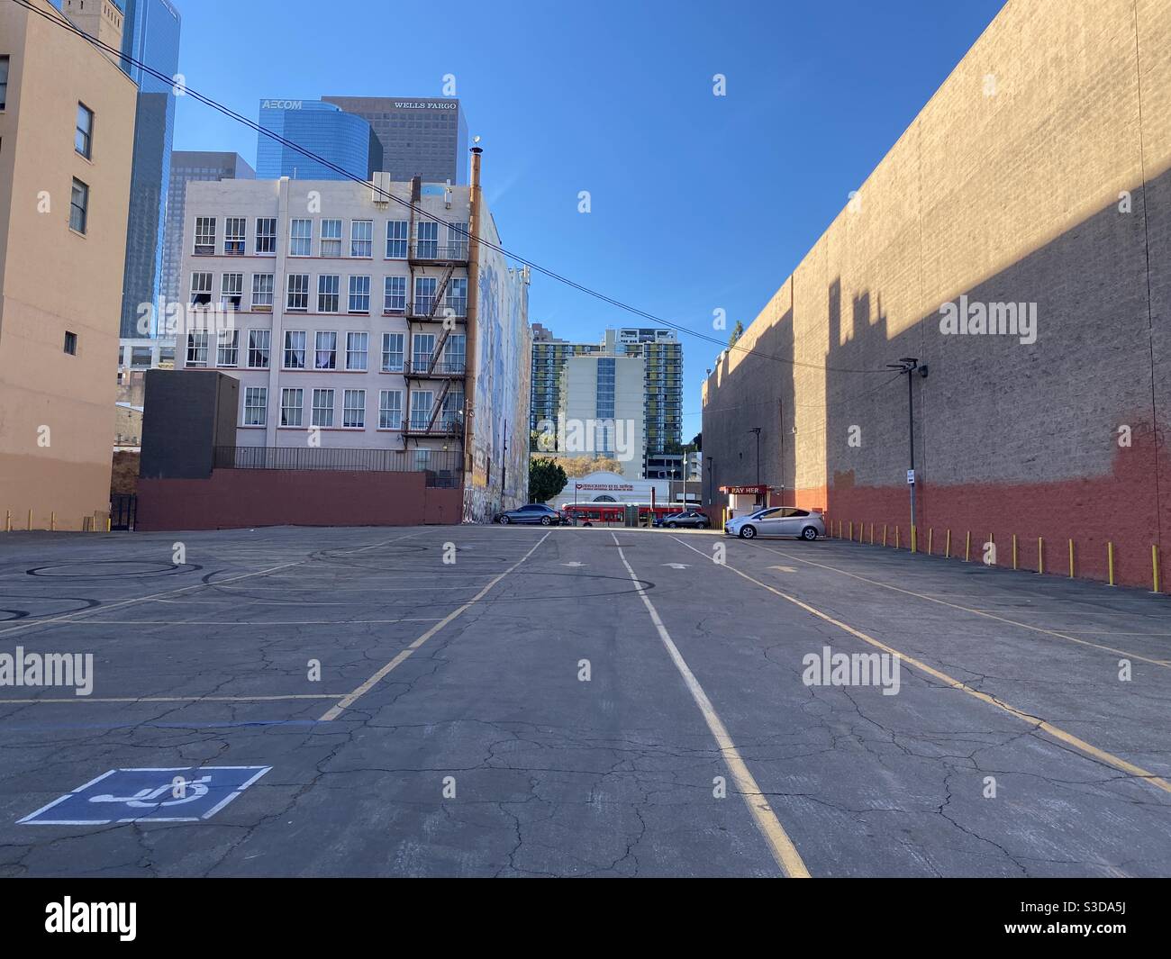 LOS ANGELES, CA, NOV 2020: mostly empty parking lot in Downtown with LA Metro red bus passing in front of a Hispanic wedding chapel at the far end, skyscrapers visible over near buildings - Smartphone Captured Stock Image