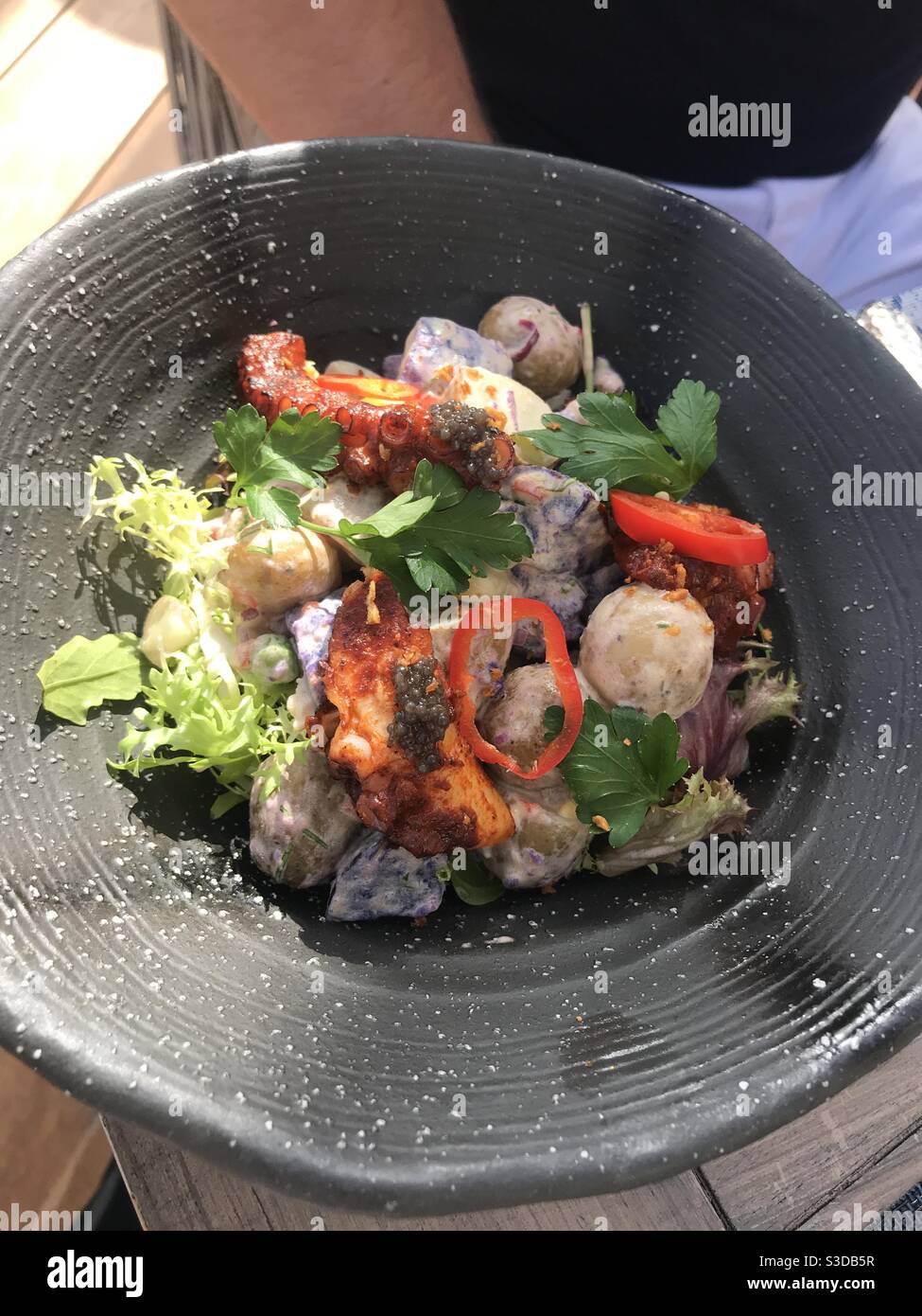 Grilled octopus salad served on an outdoor restaurant terrace - Smartphone Captured Stock Image