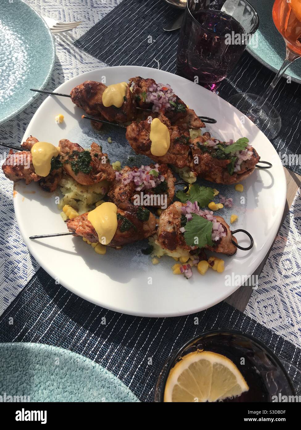 Skewers of grilled chicken thighs with sweet potatoes, corn, huancaina sauce cream and chalaca - Smartphone Captured Stock Image