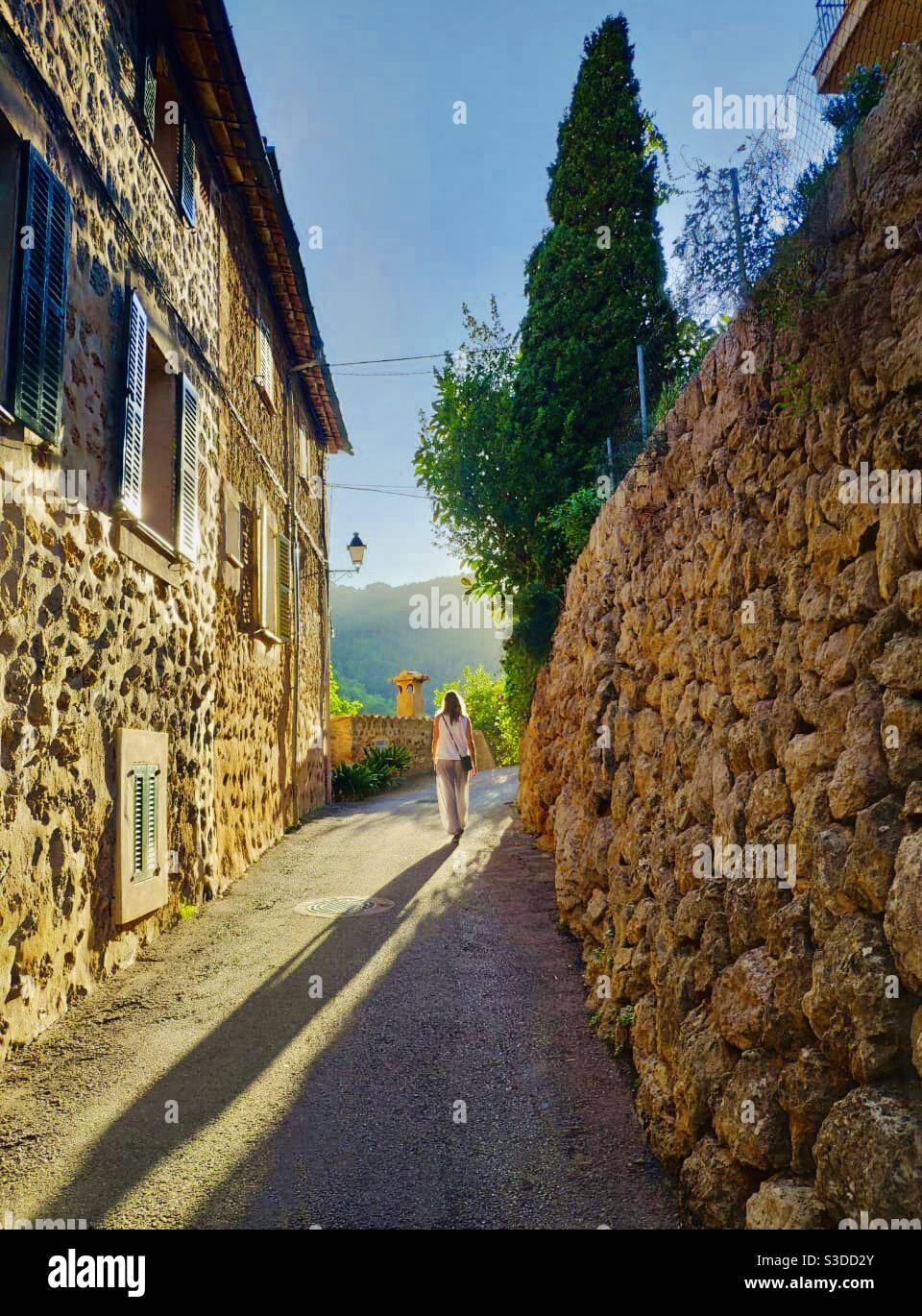 Woman walking away in the golden hour of an mountain village - Smartphone Captured Stock Image