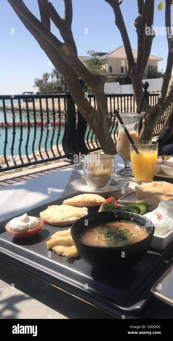 Arabic breakfast served on an outdoor restaurant terrace overlooking the sea on The Pearl island in Doha, Qatar - Smartphone Captured Stock Image
