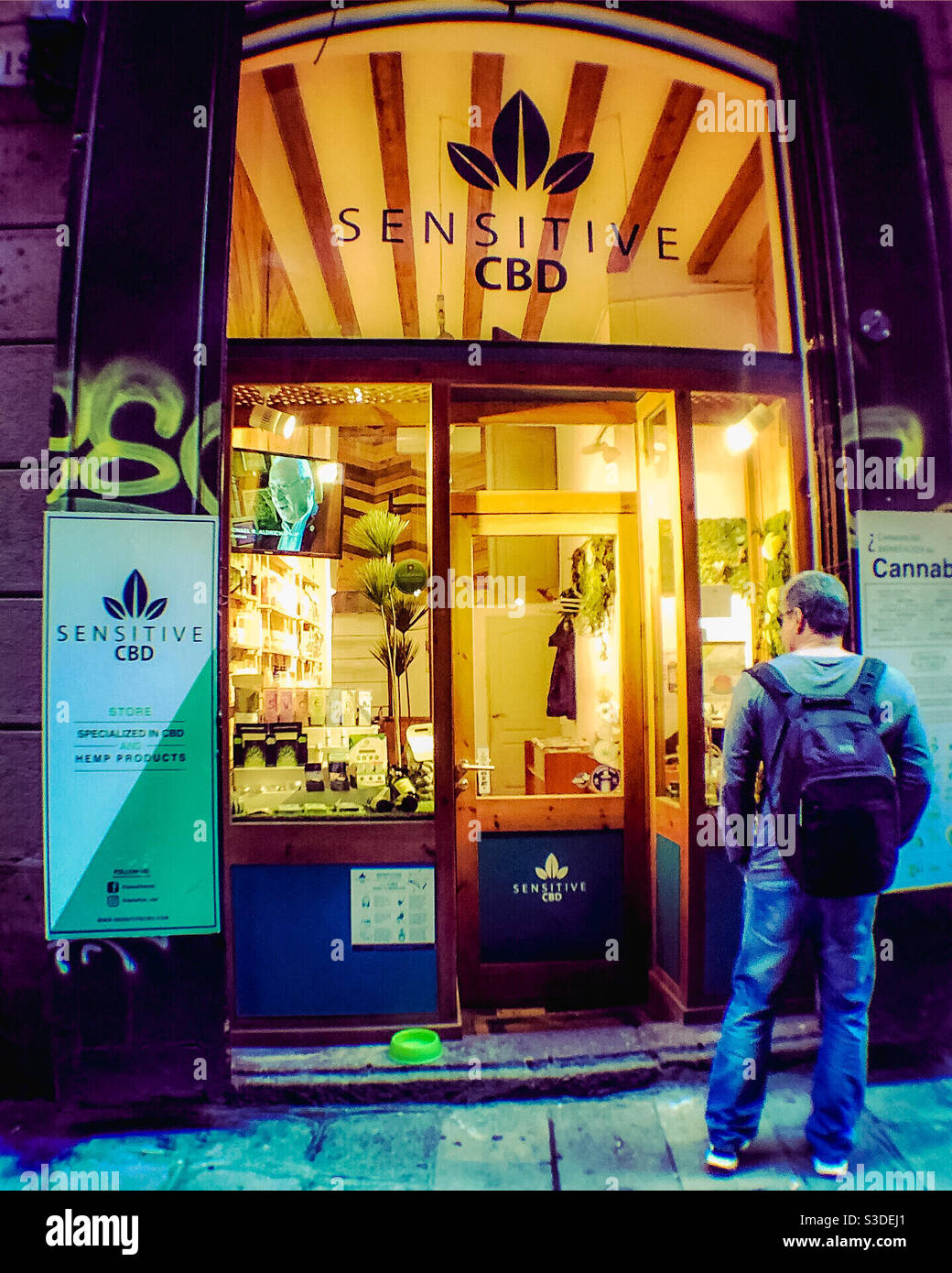 Potential customer cautiously views cannabis shop in Barcelona - Smartphone Captured Stock Image
