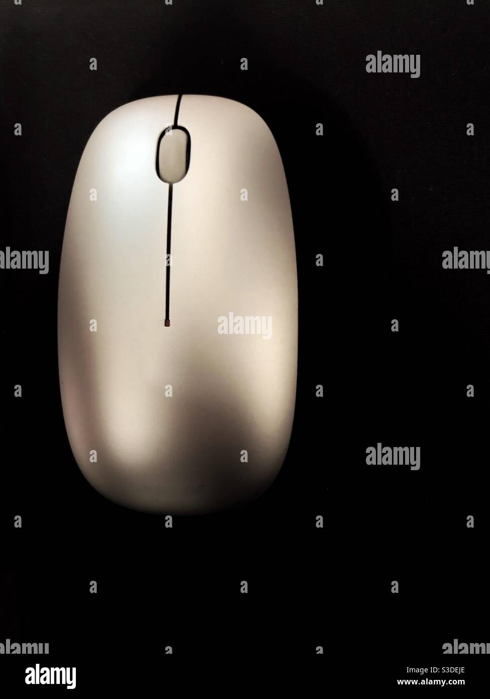 A contemporary computer mouse on a black mat from above with scroll wheel in a technology background with copy space Stock Photo