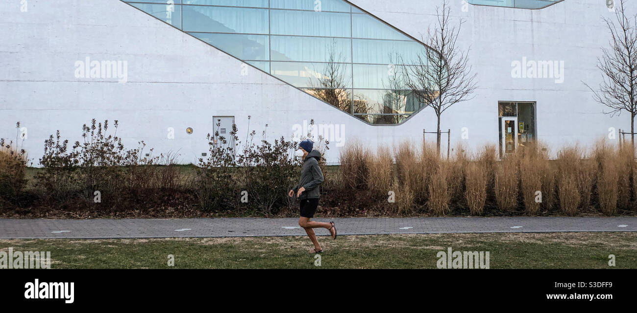 A runner passing in front of the Hunters Point Community Library, designed by Steven Holl Architects, in Long Island City, Queens - Smartphone Captured Stock Image
