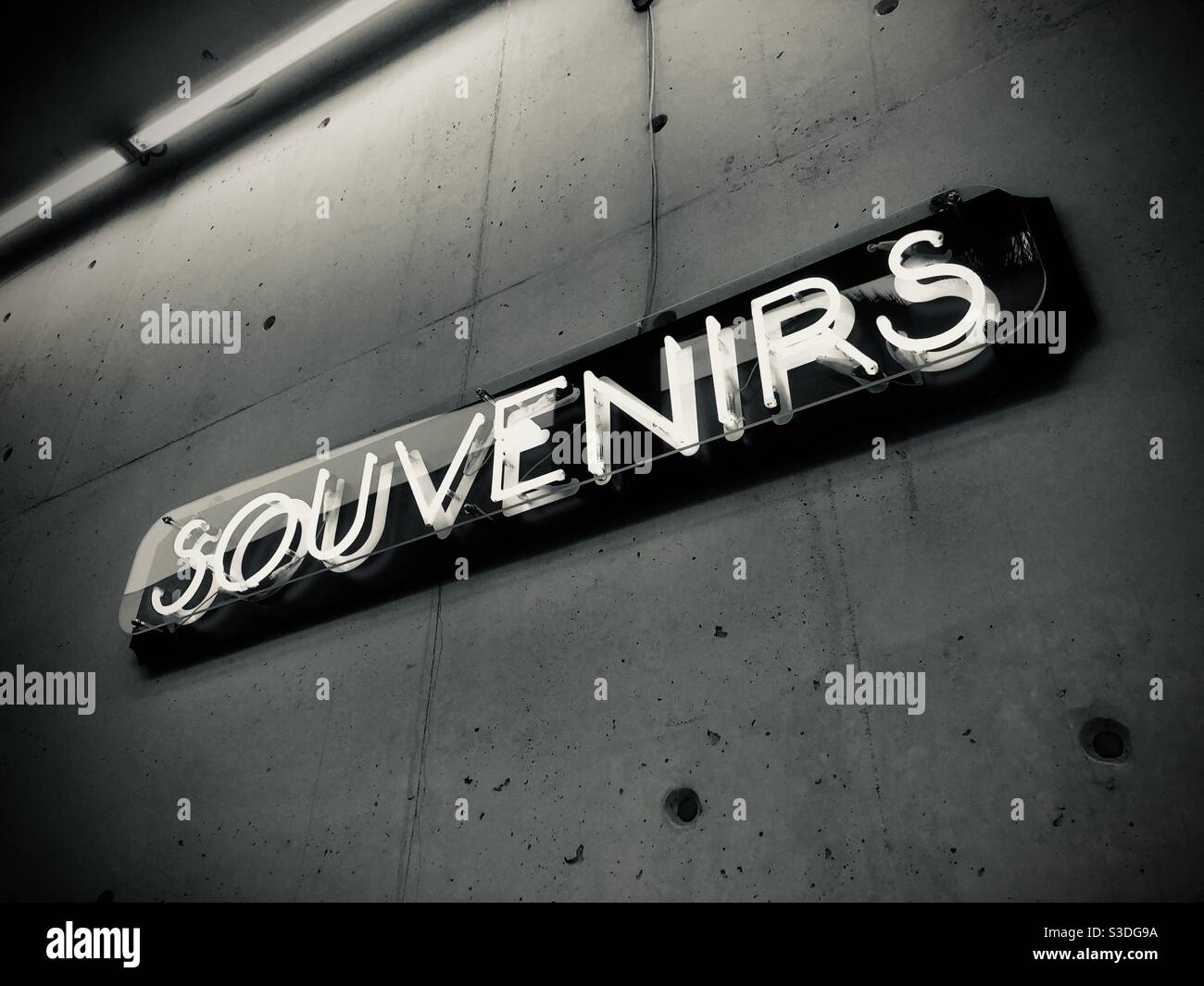 Neon light showing  the word souvenirs on a concrete wall - Smartphone Captured Stock Image